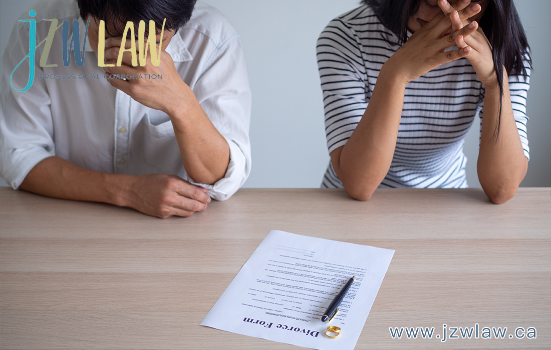 Two people sit at a table with a divorce form and pen, appearing stressed as they review the paperwork.