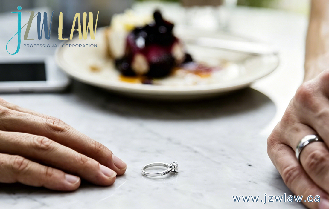 Engagement ring rests on a marble tabletop between two hands, with a blurred dessert plate in the background; law firm branding in the top-left corner and website text in the bottom-right.