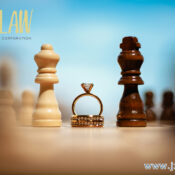 Engagement ring between white and dark chess kings on a board with a blurred law firm logo in the background