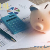 Piggy bank, calculator, and printed financial charts on a desk, representing budgeting for JZW Law services.