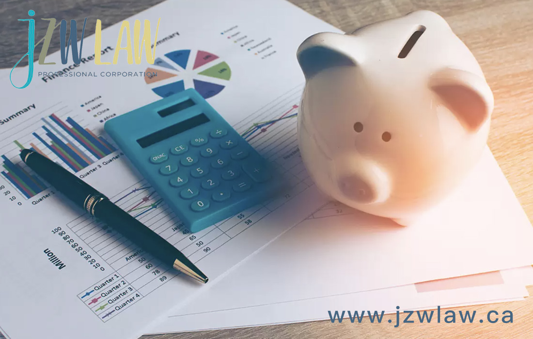 Piggy bank, calculator, and printed financial charts on a desk, representing budgeting for JZW Law services.