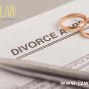 Divorce document with two gold wedding rings and a pen on top; law firm logo in the corner with the website www.jzwlaw.ca