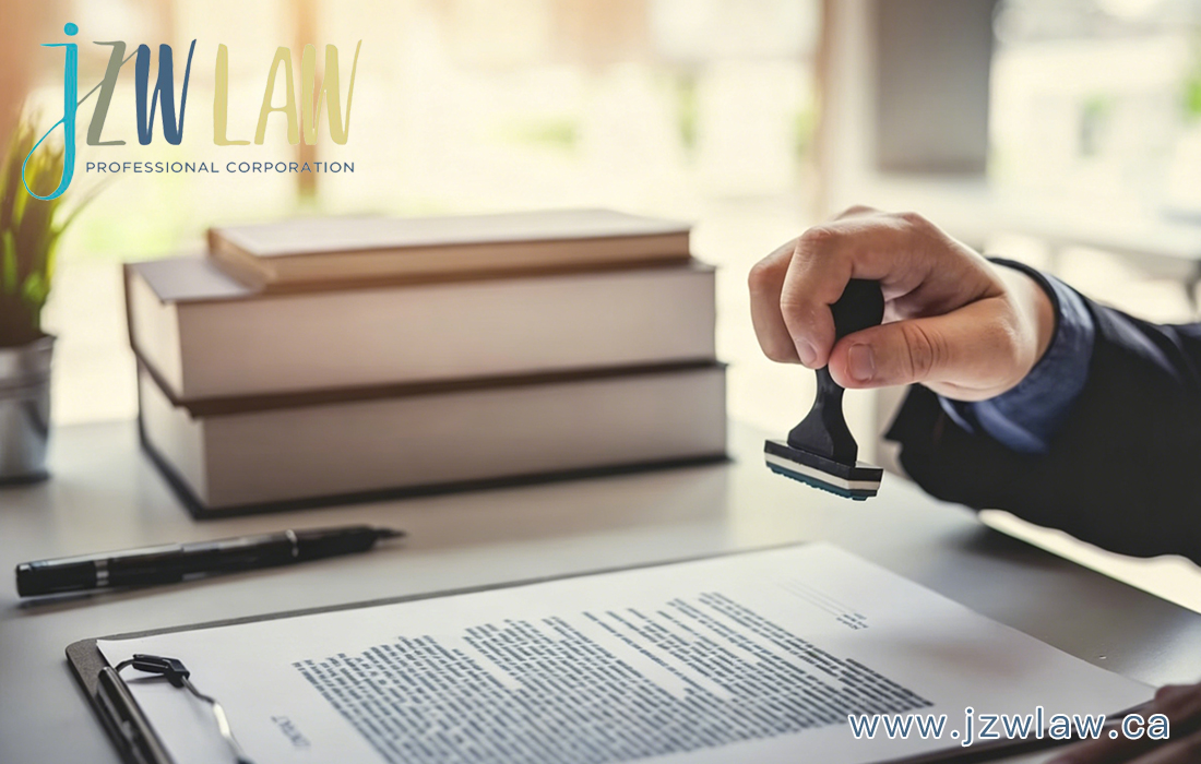 A hand stamping a contract at a desk with a stack of books; JZW Law logo top left and www.jzlaw.ca bottom right.