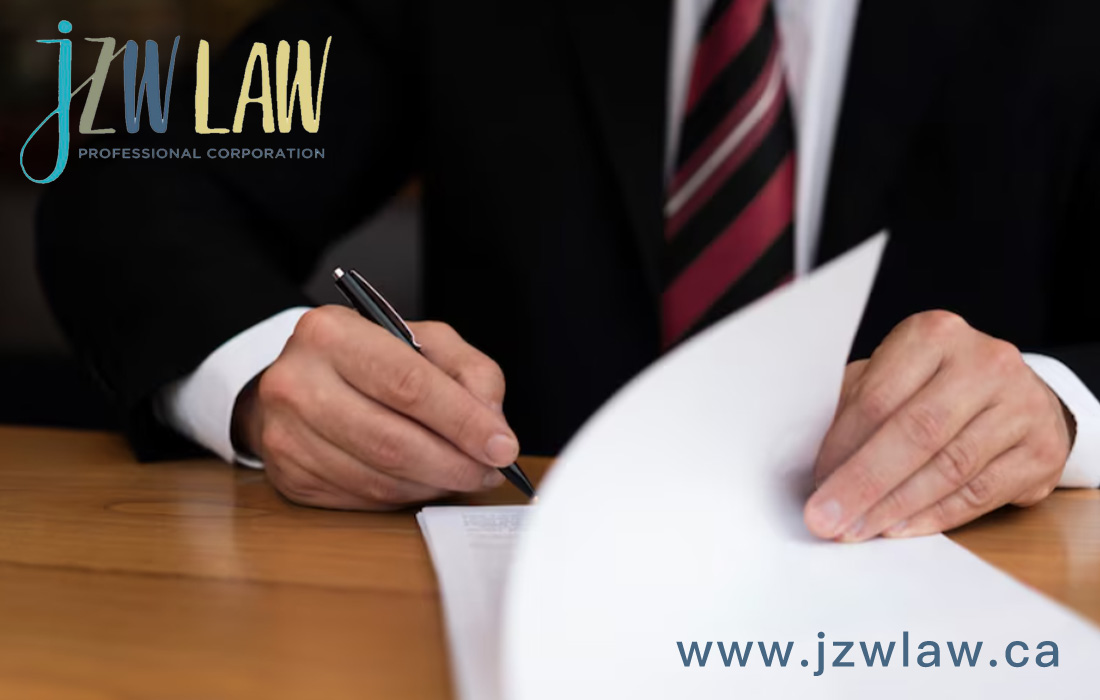 Person in a suit signing documents at a wooden desk; law firm logo in the top-left and www.jzwlaw.ca in the bottom-right.